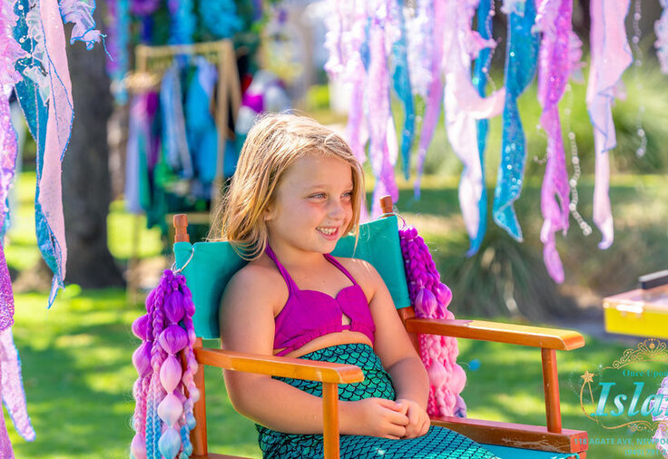 A little mermaid smiling in the traveling salon styling chair